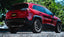 Gibson 14-20 Jeep Cherokee 3.2L 2.5in/2.25in Cat-Back Dual Split Exhaust - Stainless installed on a red SUV.