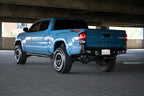 DV8 Offroad 16-23 Toyota Tacoma MTO Series Rear Bumper installed on a blue Tacoma with offroad wheels in a parking garage.
