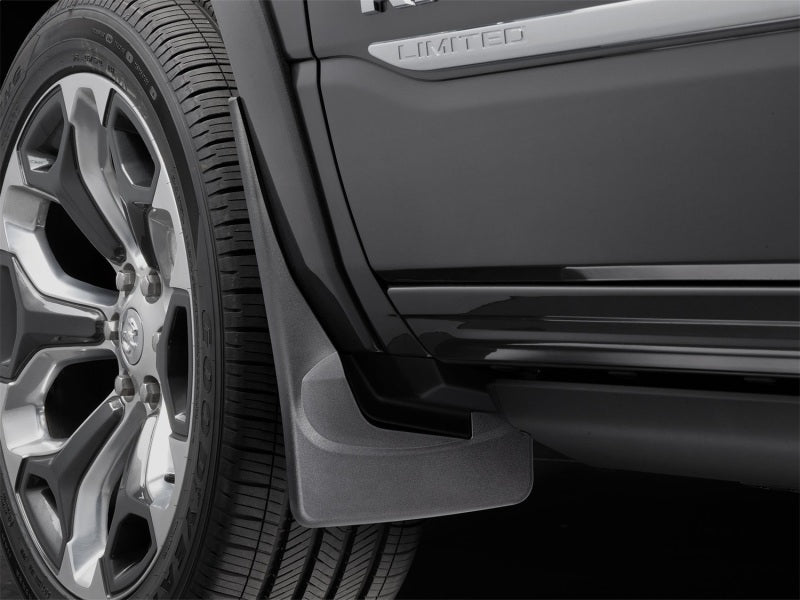 WeatherTech 19+ Dodge Ram w/ Factory Flares Front No Drill Mudflaps - Black close-up with tire and rim.