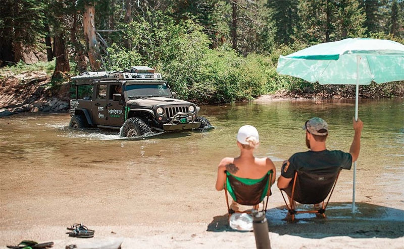 MagnaFlow 12-18 Jeep Wrangler 2.5in Overland Series Cat-Back Exhaust in action near water with offroad enthusiasts.