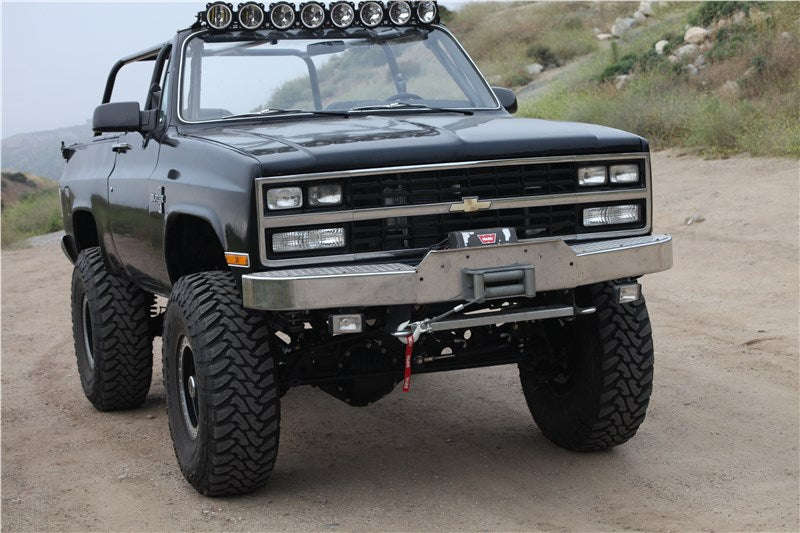 Custom lifted off-road truck with LED light bar and winch.