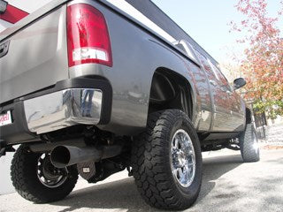 Silver truck with offroad tires and suspension lift kit.