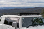 ARB Base Rack Deflector Base Rack 1770040 and Base Rack Mount Kit 17920020 on Toyota FJ Cruiser with scenic background.