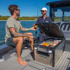 Two men enjoying drinks from an ARB Ss Fridge 63 Quart Usa B Plug on a boat.