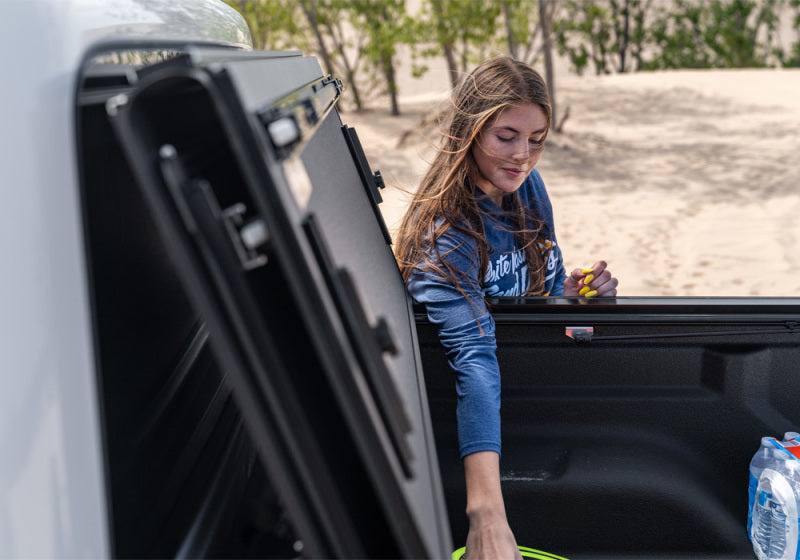 Woman accessing gear from BAK 2020 Jeep Gladiator 5ft Bed BAKFlip MX4