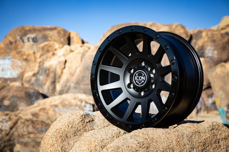 ICON Compression 17x8.5 6x5.5 25mm Offset 5.75in BS 95.1mm Bore Double Black Wheel on rugged terrain.