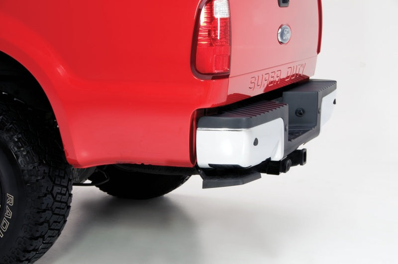 AMP Research 1999-2016 Ford F-250/350/450 BedStep - Black installed on a red truck's bumper.