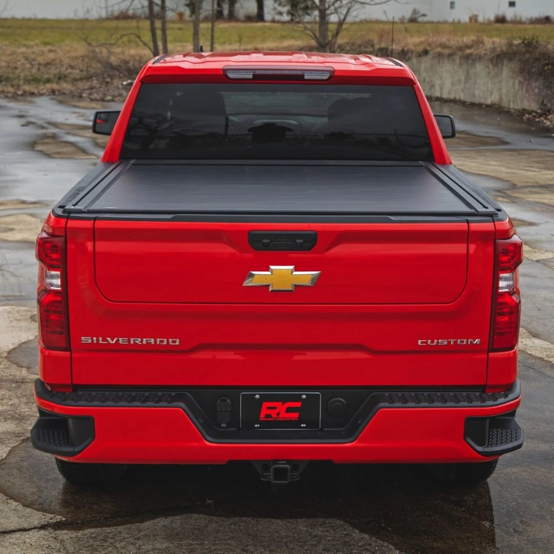 Red Chevrolet Silverado with a tonneau cover and custom features, showcasing offroad accessories and performance upgrades.