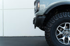 DV8 Offroad 21-23 Ford Bronco Capable Bumper Front License Plate Mount on offroad truck with oversized tires.