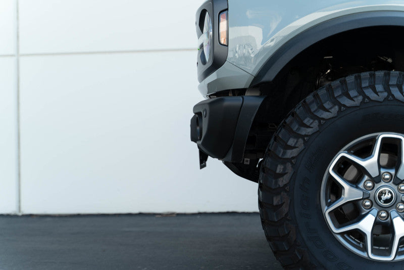 DV8 Offroad 21-23 Ford Bronco Capable Bumper Front License Plate Mount on offroad truck with oversized tires.