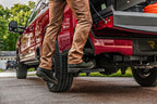 Person using AMP Research 2023 Ford F-250 Super Duty BedStep - Black for easy access.