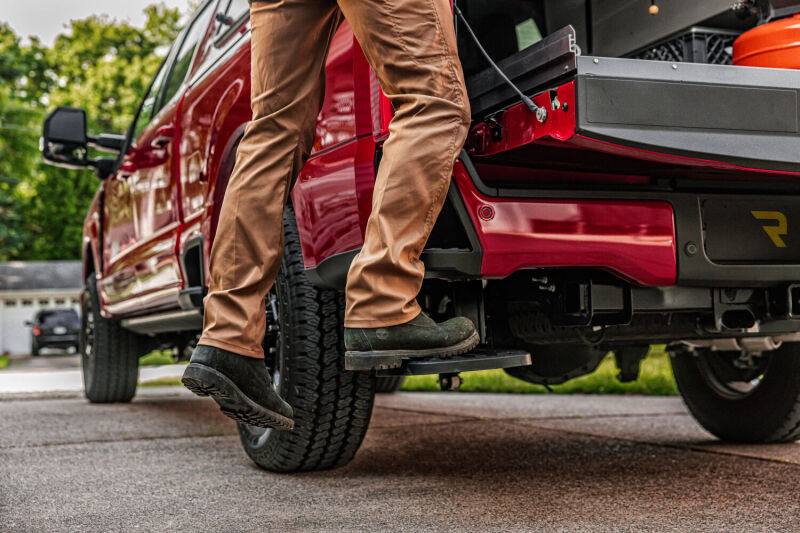 Person using AMP Research 2023 Ford F-250 Super Duty BedStep - Black for easy access.