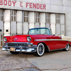 Classic red convertible car parked near a vintage body shop.