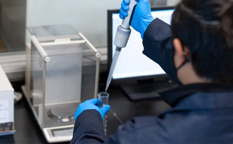 Scientist using a pipette in a laboratory setting.