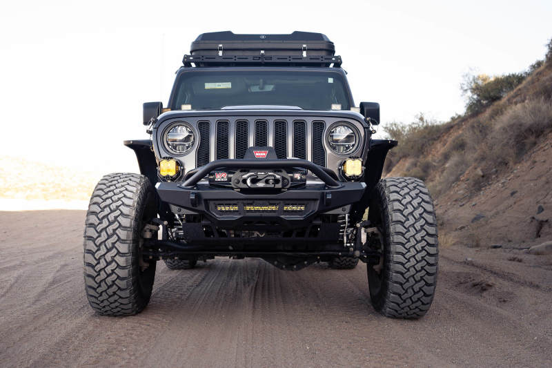 DV8 Offroad 18-23 Wrangler JL/Gladiator JT Spec Series Front Bumper on rugged terrain with offroad tires.