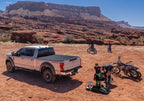 BAK 17-23 Ford Super Duty Revolver X4s 6.10ft Bed Cover in outdoor setting with offroad bikes and gear.