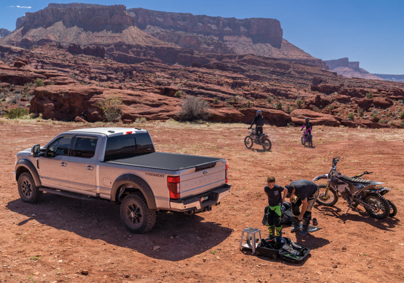 BAK 17-23 Ford Super Duty Revolver X4s 6.10ft Bed Cover in outdoor setting with offroad bikes and gear.