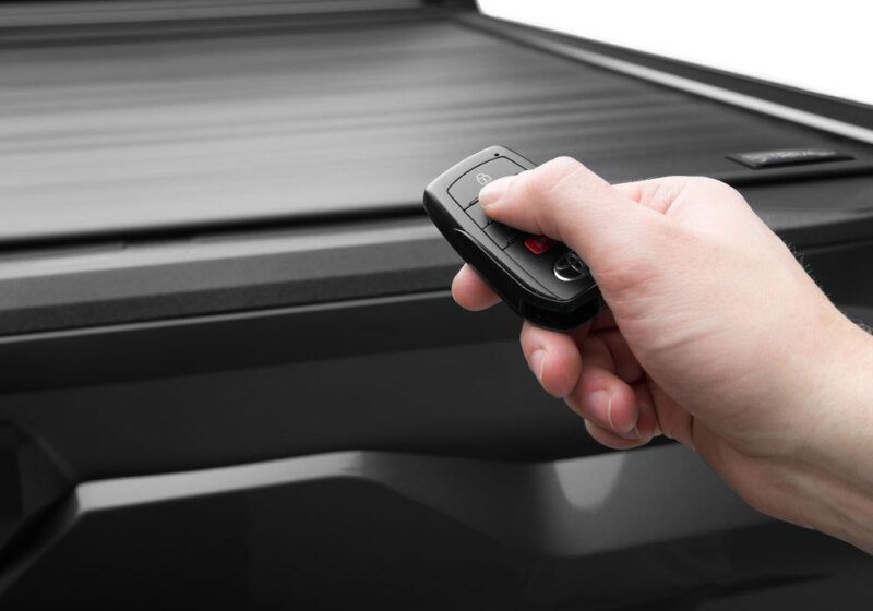 Hand using key fob to operate Retrax 2024 Ford F-150 SuperCrew/Super Cab 5.5ft. Bed Retrax EQ truck bed cover.