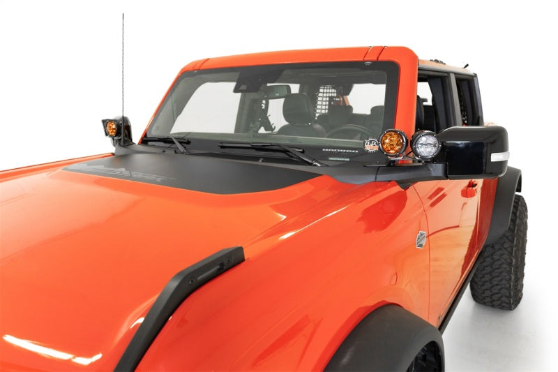 Addictive Desert Designs21-23 Ford Bronco/Raptor Dual Ditch Light Brackets mounted on orange truck for offroad lighting.