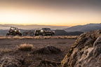 Fox 20+ GM 2500/3500 HD 2.0 Performance Series IFP Front w/UCA Shock 1.5-2.5in Lift with offroad vehicle at sunset.