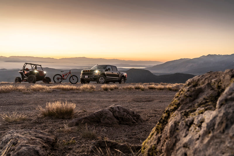 Fox 20+ GM 2500/3500 HD 2.0 Performance Series IFP Front w/UCA Shock 1.5-2.5in Lift with offroad vehicle at sunset.