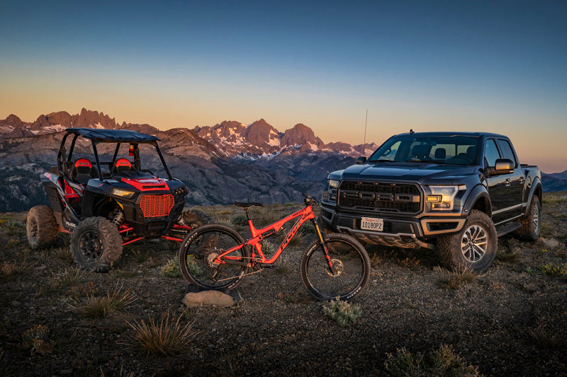 Fox 20+ GM 2500/3500 HD 2.0 Performance Series IFP Rear Shock 0-1in Lift with off-road vehicles in scenic landscape.