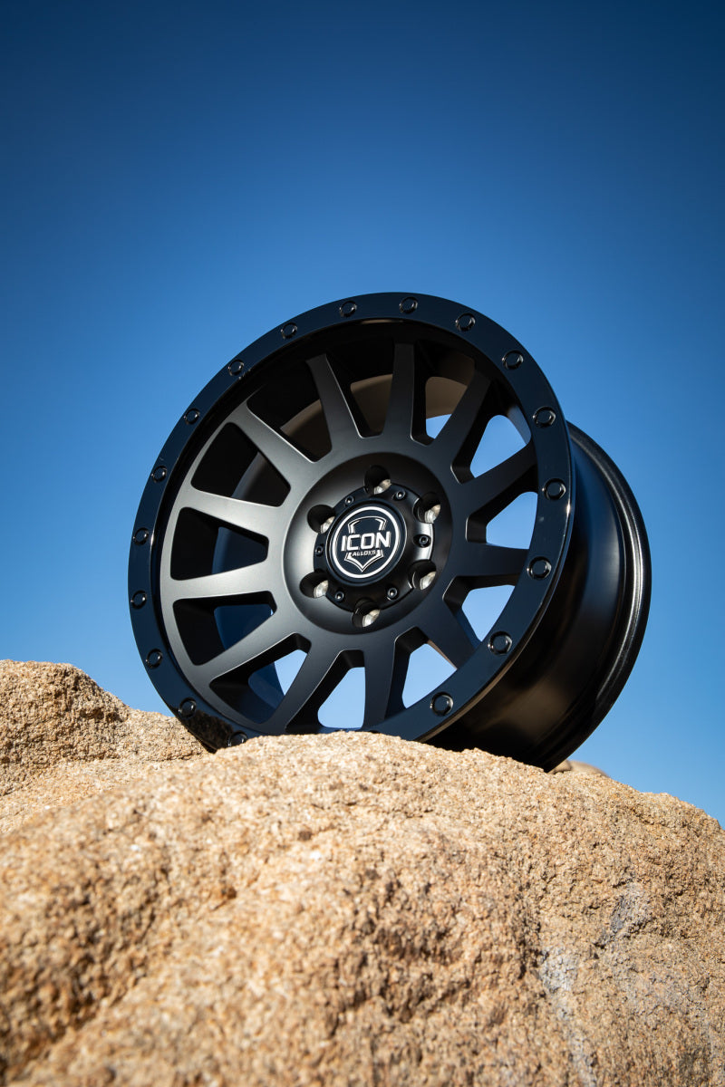 ICON Compression 17x8.5 6x5.5 25mm Offset 5.75in BS 95.1mm Bore Double Black Wheel on rock background.