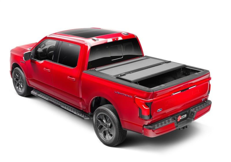 BAK 21-22 Ford F-150 (Incl. 2022 Lightning) BAKFlip MX4 5.7ft Bed Cover - Matte Finish installed on a red truck.