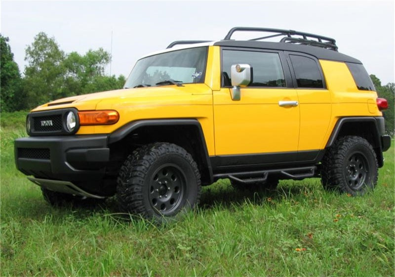 N-Fab Nerf Step 06-17 Toyota FJ Cruiser SUV 4 Door - Tex. Black - W2W - 2in. on yellow offroad vehicle in grass.