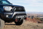 Body Armor 4x4 12-15 Toyota Tacoma HiLine Front Winch Bumper on off-road terrain, showcasing durable design and performance features.