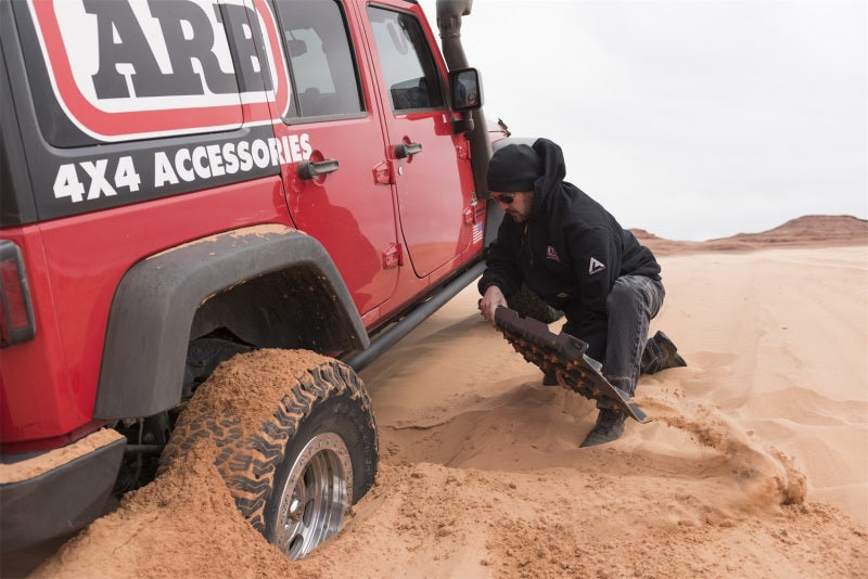 Man using ARB Tred Pro Red recovery board on off-road 4x4.