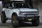 DV8 Offroad 21-22 Ford Bronco Factory Front Bumper Licence Relocation Bracket - Front on a modified Bronco in a garage.